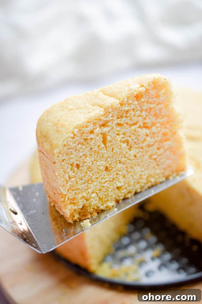 A slice of the Instant Pot cornbread is held on a pie server.