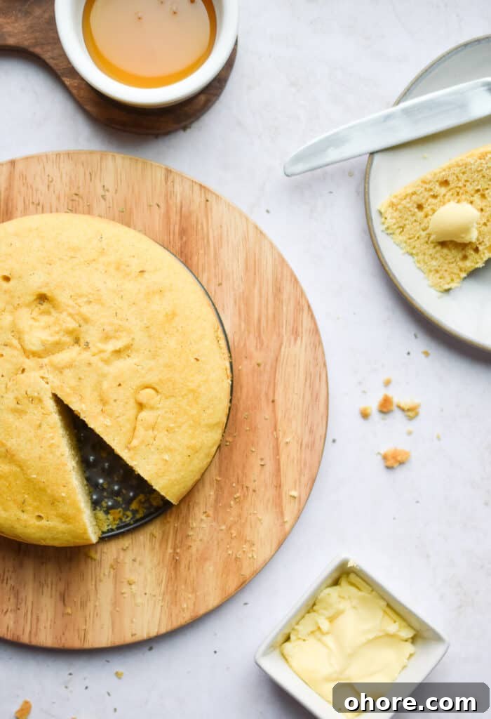 The Instant Pot cornbread is on a circle platter and a slice is cut from it.