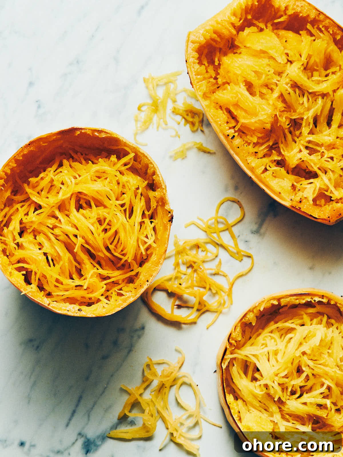 How to Cook Spaghetti Squash: Simple Oven and Microwave Methods 2 Spaghetti squash cooked three ways with noodles scooped out sitting on a marble surface