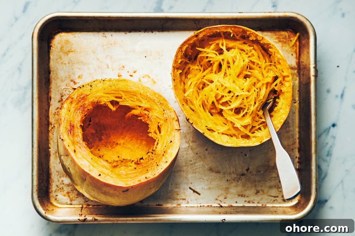 How to Cook Spaghetti Squash: Simple Oven and Microwave Methods 7 Spaghetti squash cut in half crosswise and cooked on a metal baking sheet with noodles scooped out