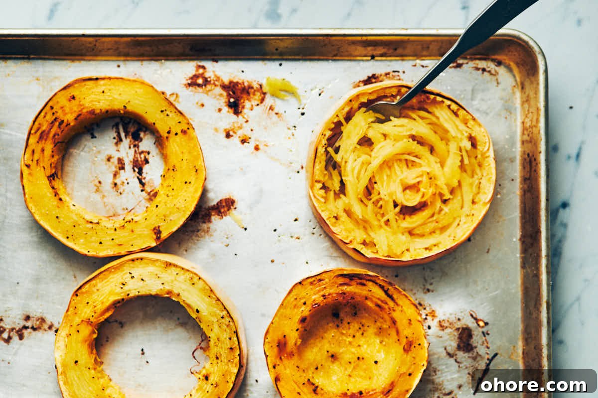 How to Cook Spaghetti Squash: Simple Oven and Microwave Methods 9 Spaghetti squash cut into rings cooked on a metal baking sheet with noodles scooped out