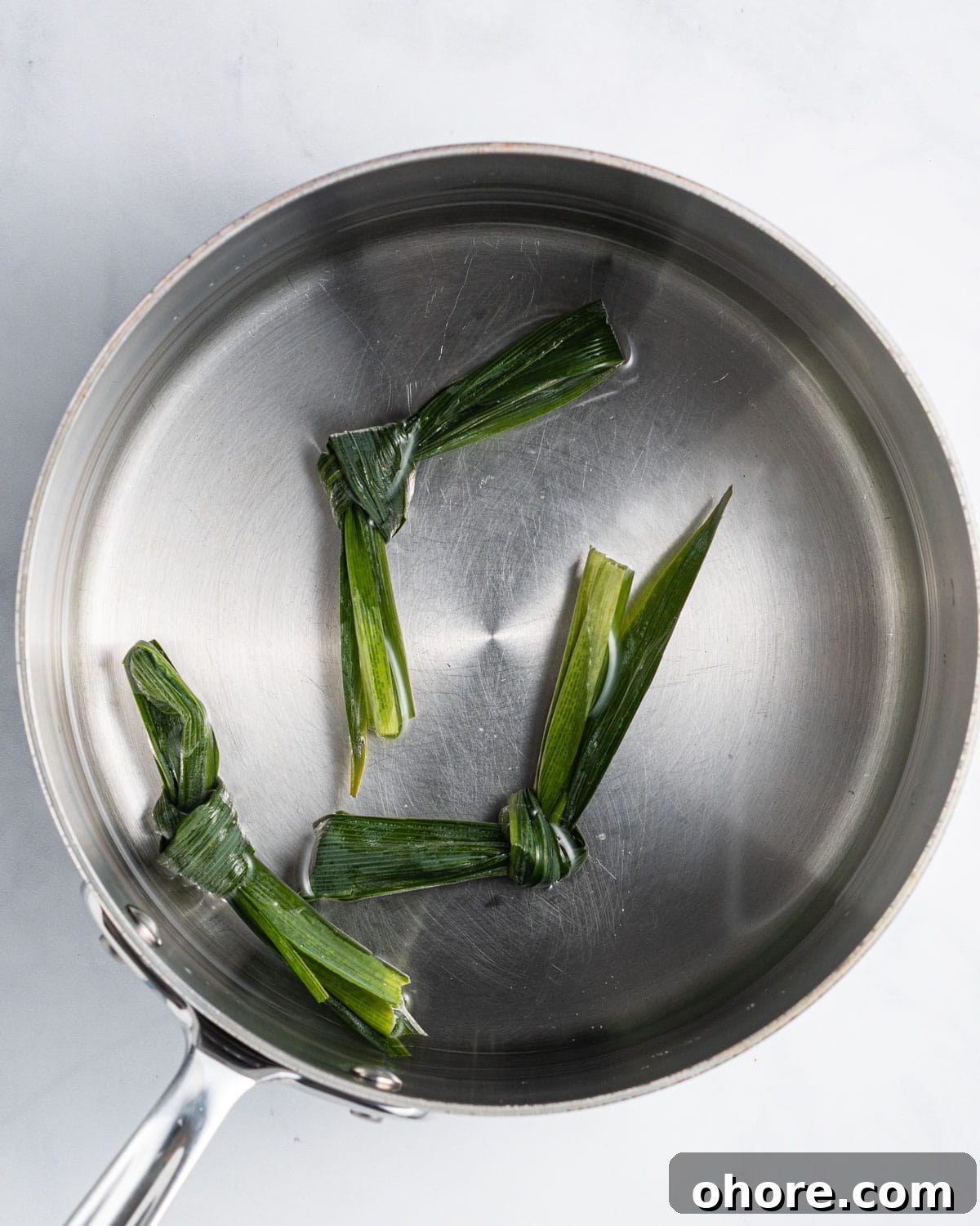 Three pandan leaves tied in a knot in a pot of water.