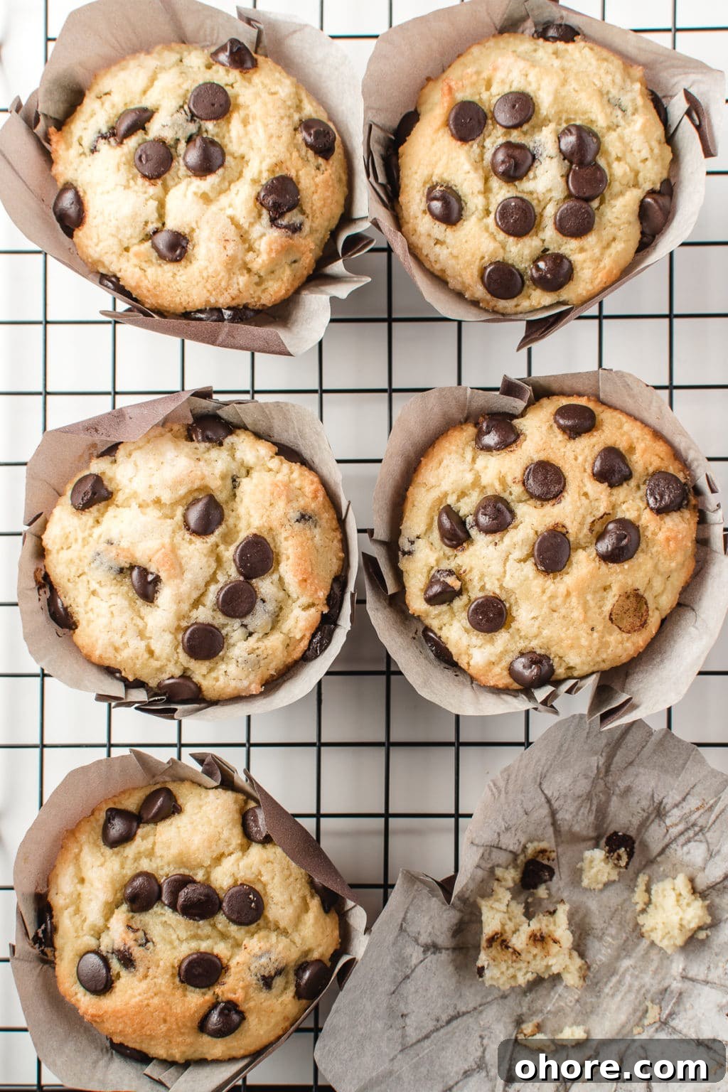 Bakery-style low-carb chocolate chip muffins resting on a cooling grid. The image is intended to show a keto-friendly, gluten-free breakfast option for chocolate lovers