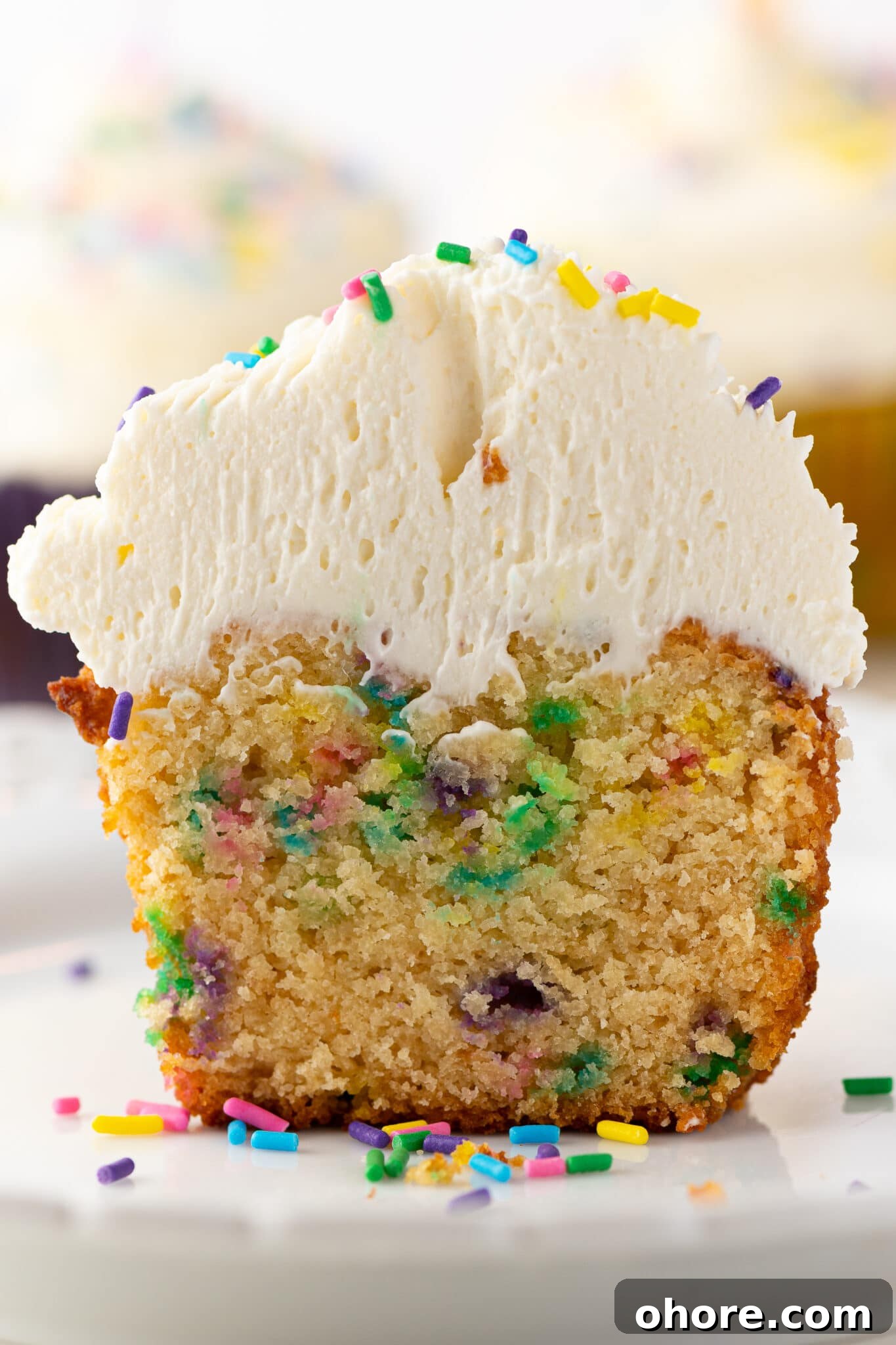 Low-carb cupcakes with sprinkles and frosting piled high.  The muffin is split in  half to show the texture inside. The image intended to show an example of keto muffin recipes you can make on a carb restricted diet. 