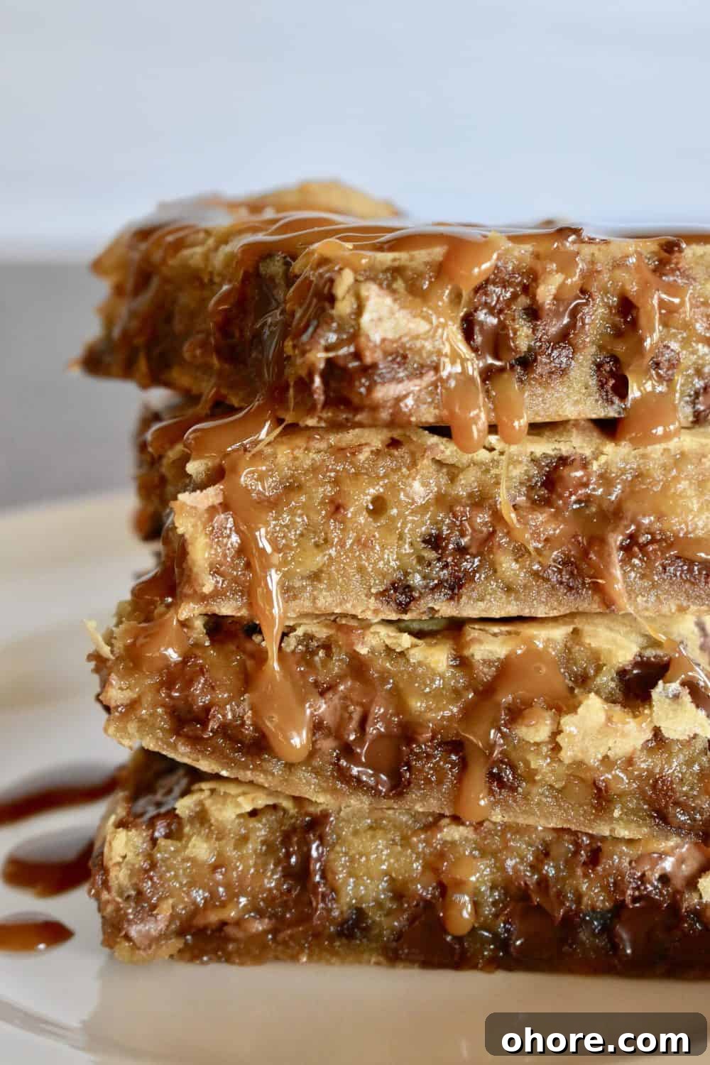 Milky Way Blondies with Caramel and Chocolate Delight 2 Milky Way Blondies stacked with caramel sauce drizzle.
