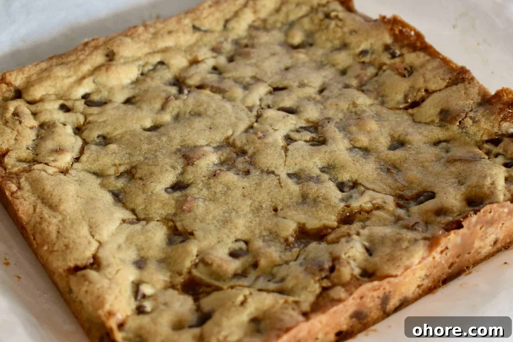 Milky Way Blondies with Caramel and Chocolate Delight 11 Baked Milky Way Blondies on white parchment paper.