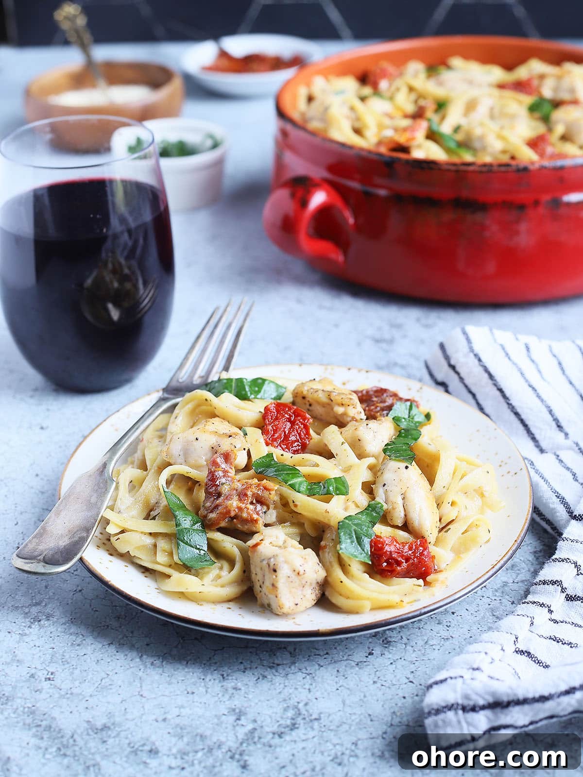 Creamy Marry Me Chicken Pasta Recipe for Weeknight Dinner 6 Serving of Marry Me Chicken Pasta with a glass of red wine and a serving bowl of pasta in the background.