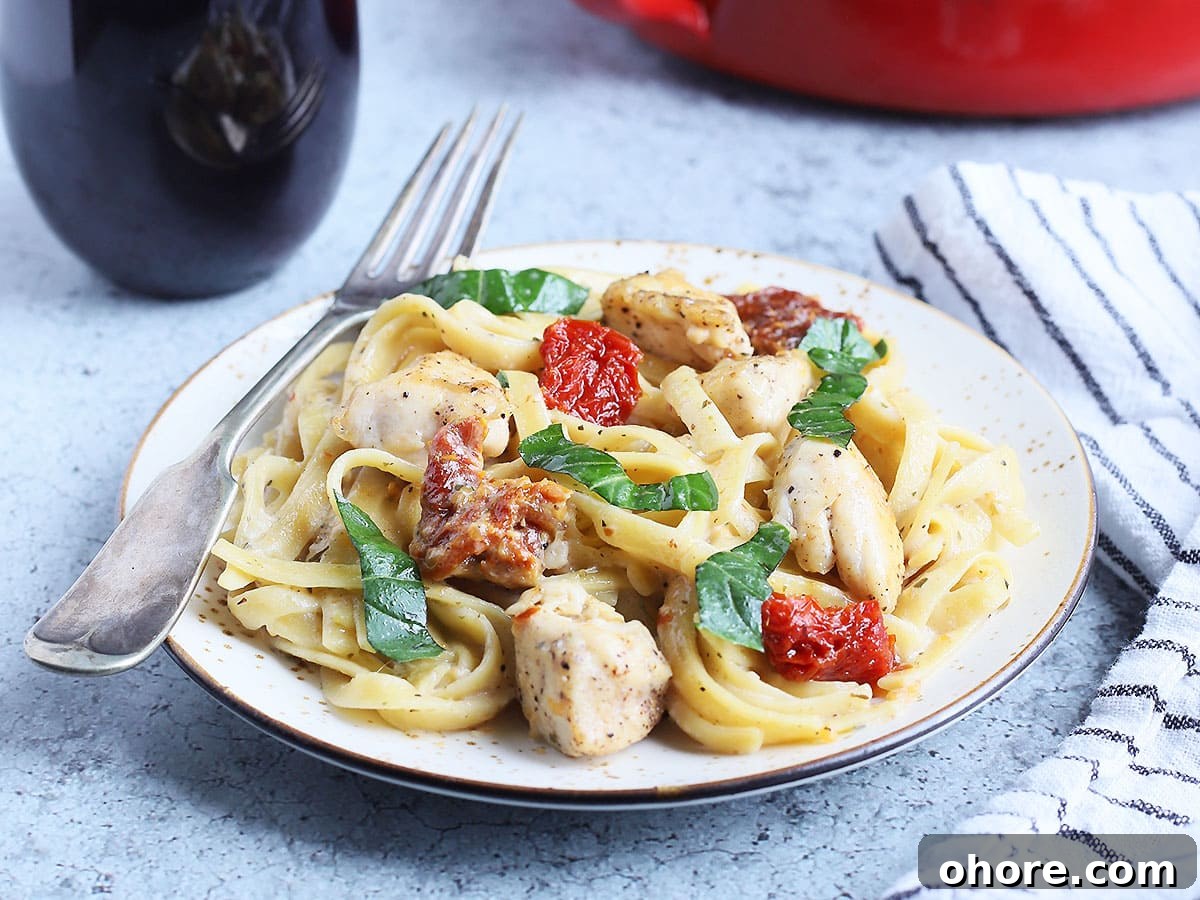 Creamy Marry Me Chicken Pasta Recipe for Weeknight Dinner 7 Serving of Marry Me Chicken Pasta with a glass of red wine and a serving bowl of pasta in the background.