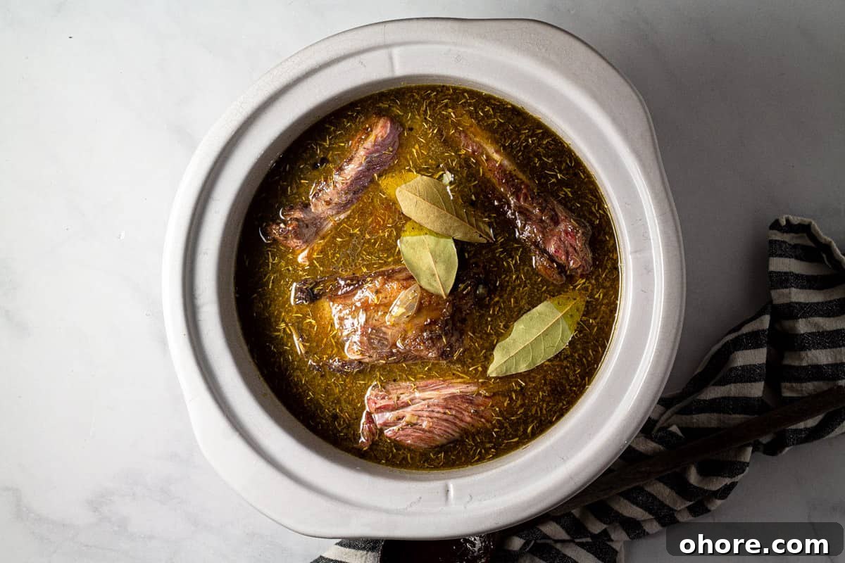 Large crock pot insert filled with seared short ribs and beer