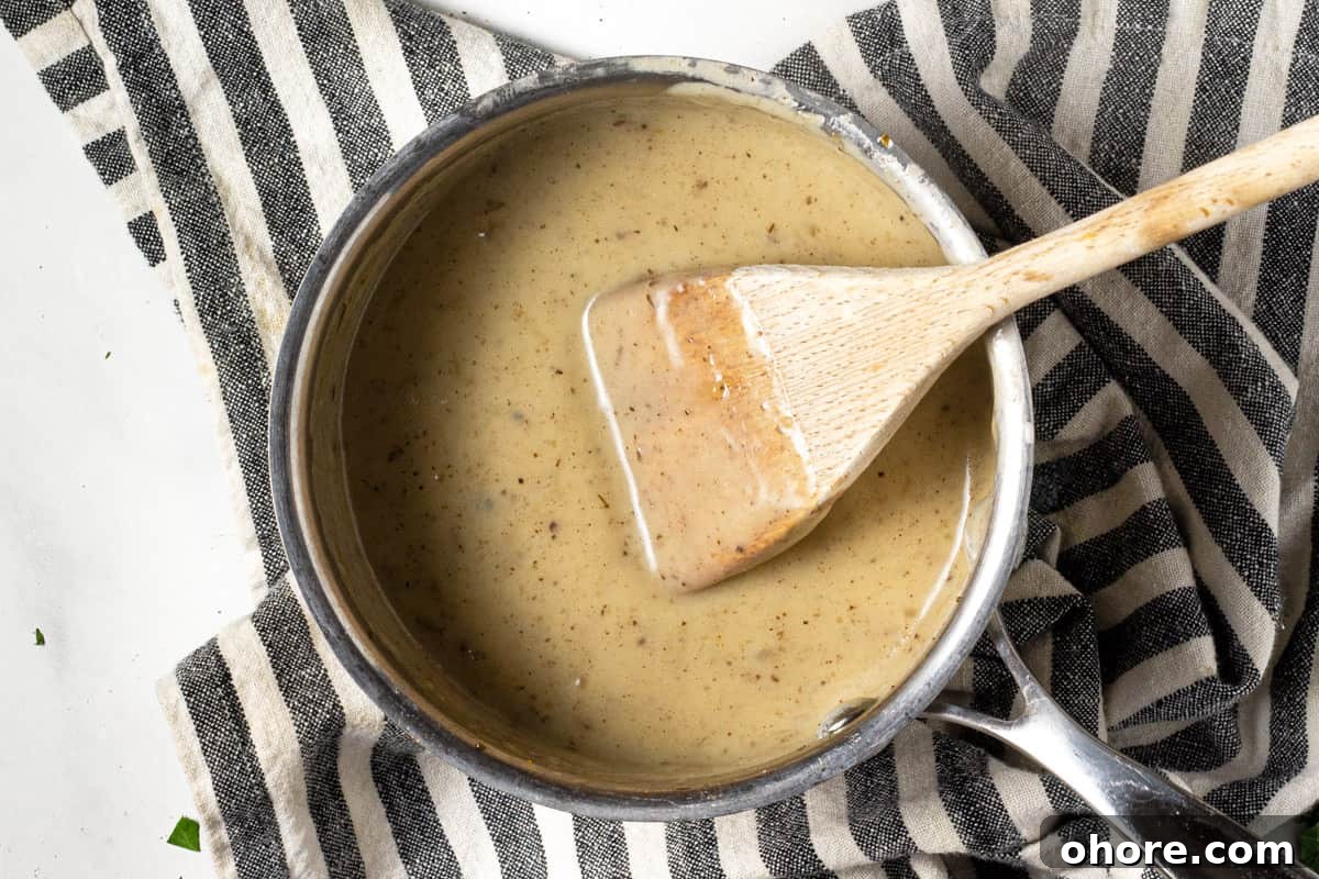 A small sauce pan filled with creamy gravy from beer braised short ribs