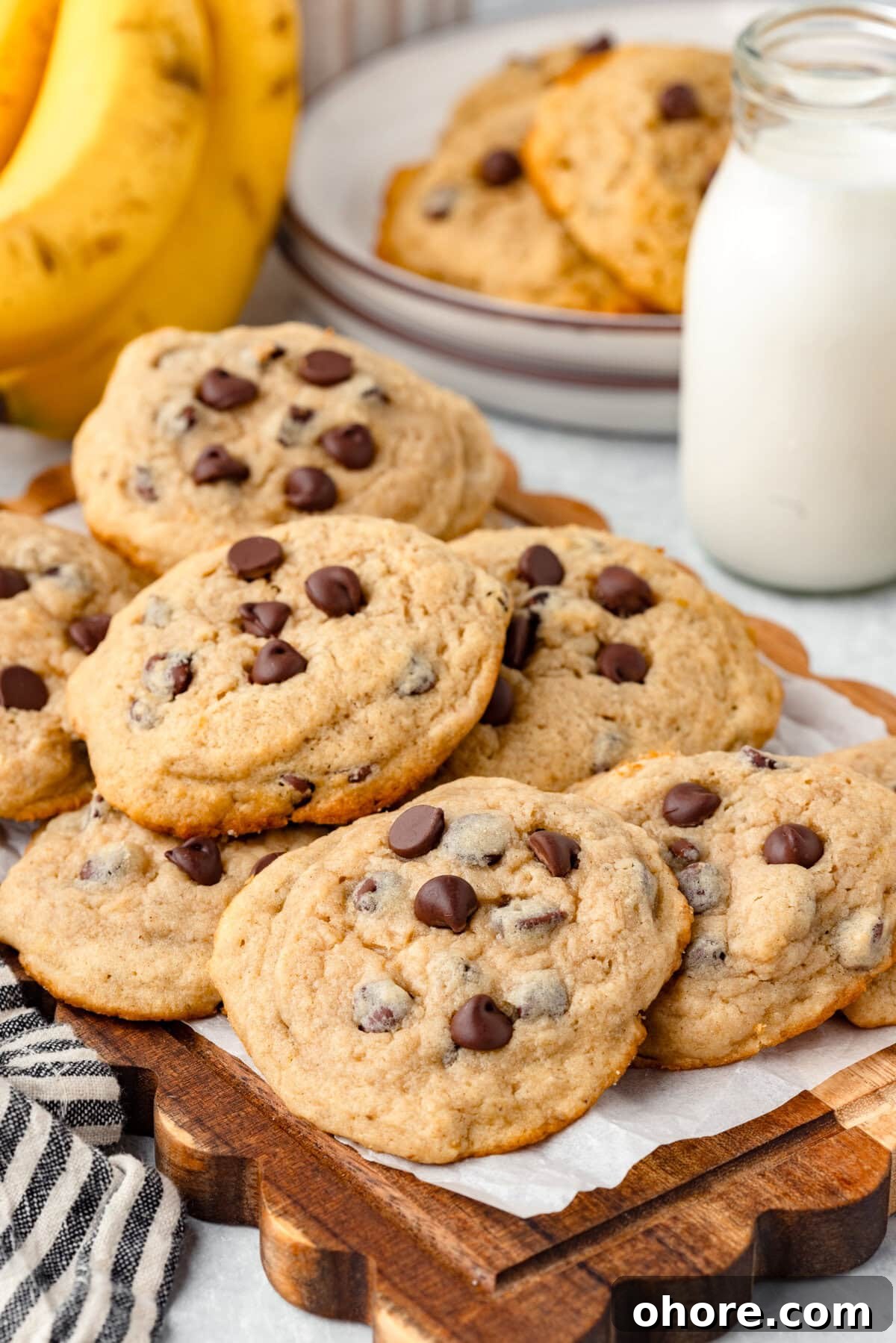 Banana Chocolate Chip Cookies Recipe — Moist Banana Cookies with Chocolate Chunks 2 1. Soft chocolate chip cookies with golden edges, on a wooden serving tray.