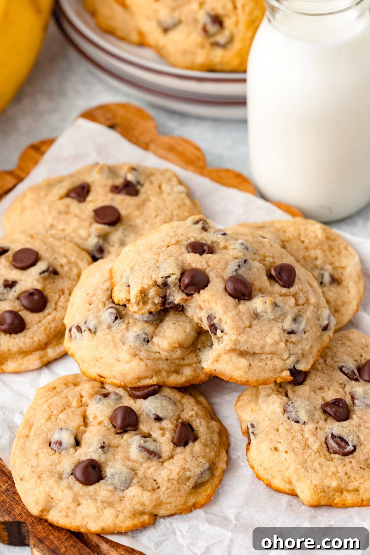 Banana Chocolate Chip Cookies Recipe — Moist Banana Cookies with Chocolate Chunks 5 Butter cookies with chocolate chips on a wooden tray, with a jar of milk in the background, styled for a cozy snack.