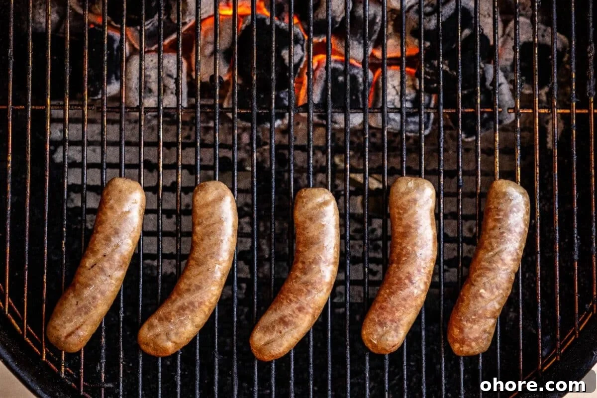 Perfectly Grilled Bratwurst: Juicy Sausage on the Grill 3 Bratwursts on grill grates over charcoal.