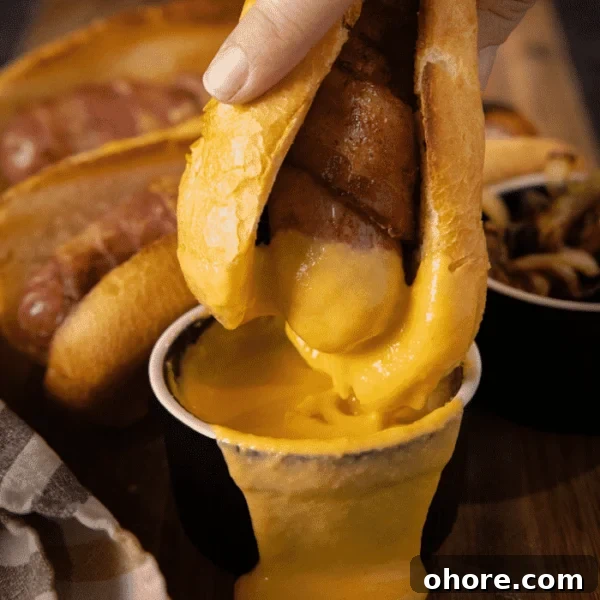 Perfectly Grilled Bratwurst: Juicy Sausage on the Grill 5 A sausage on a bun being dipped in cheese sauce.