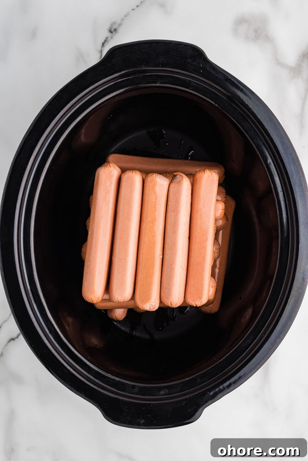 Slow Cooker Hot Dogs: Juicy, Fuss-Free Recipe and Tips 4 black slow cooker with 24 hots dogs layered
