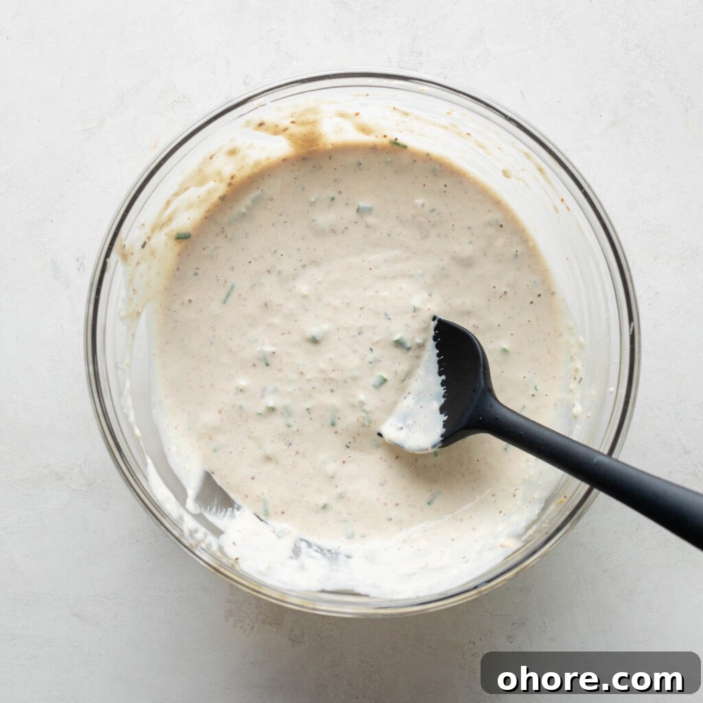 Creamy Horseradish Sauce for Prime Rib: Tangy Roast Beef Topping 7 Chives folded into Horseradish Prime Rib Sauce with black silicone spatula.