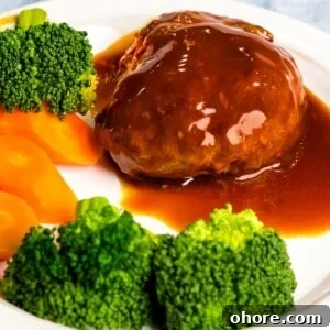 Japanese Hambagu (Hamburger Steak) Recipe — Authentic Pan-Fried Steak 19 Japanese hamburger steak (hambāgu ハンバーグ) on a white plate next to broccoli and carrots.