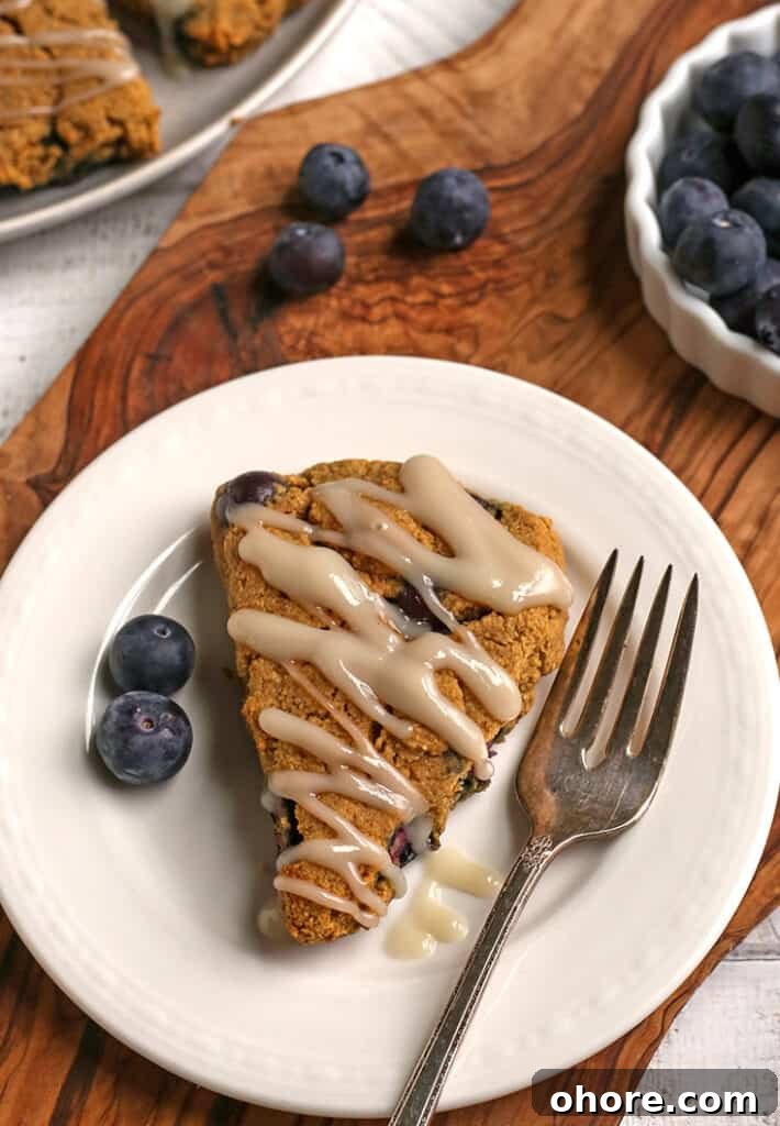 Paleo Blueberry Scones Recipe – Flaky, Grain-Free Breakfast Treat 3 paleo blueberry scone on a plate with blueberries in the background