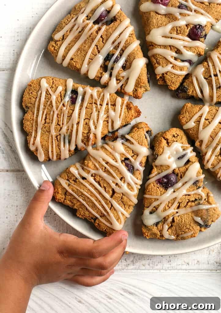 Paleo Blueberry Scones Recipe – Flaky, Grain-Free Breakfast Treat 5 a little hand reaching for a paleo blueberry scone