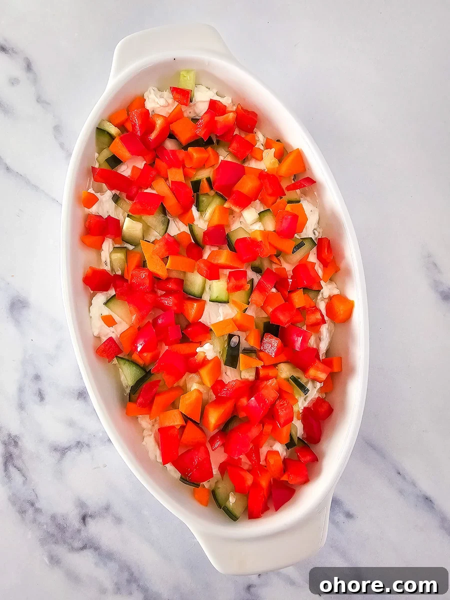 Creamy Vegetable Pizza Dip Recipe for Parties and Game Day 9 Red peppers are spread on top of cucumbers in bowl of dip.