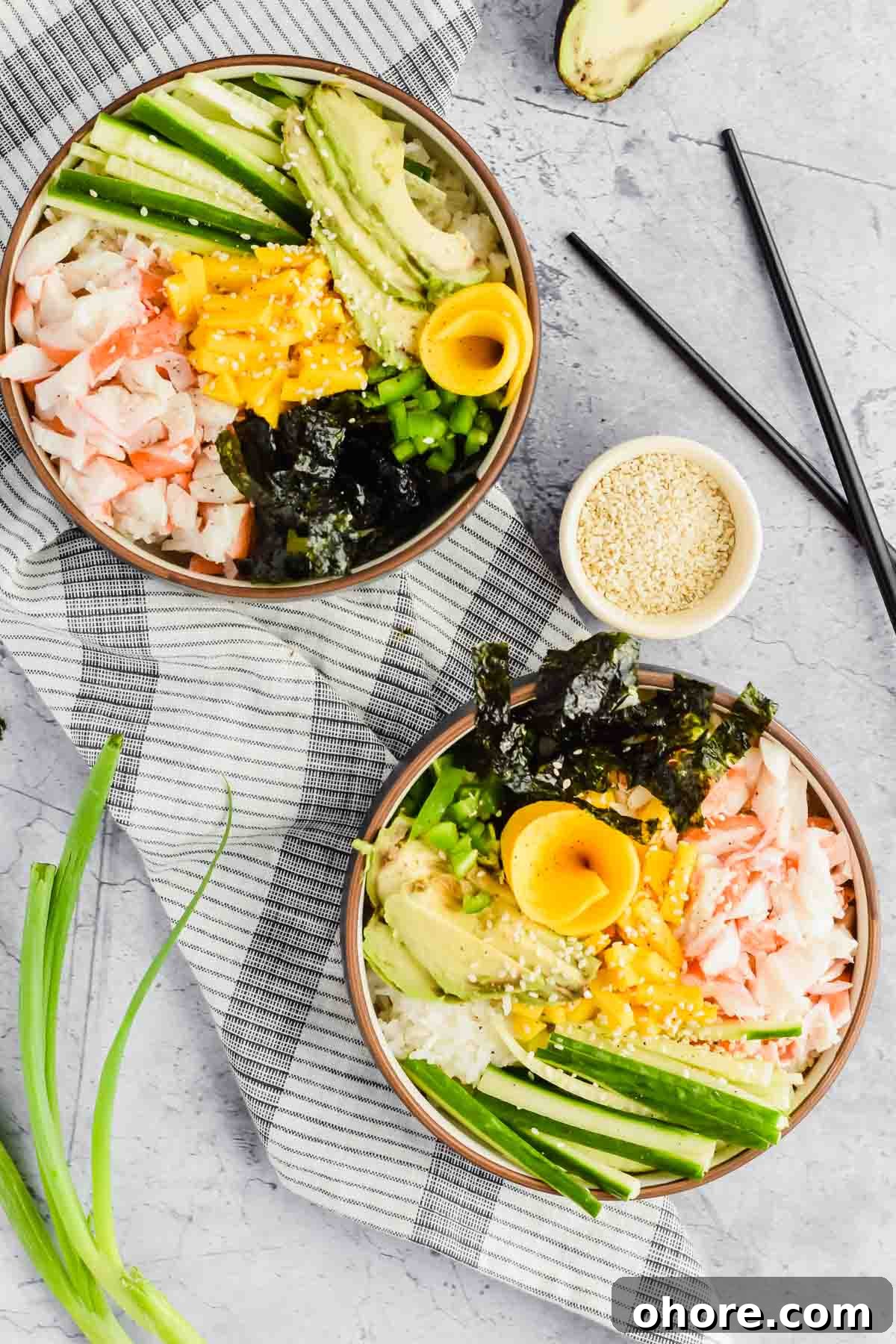 California Roll Bowl Recipe: Sushi-Inspired Deconstructed Bowl Guide 6 two california roll poke bowls in black bowl on top of striped tea towel beside bowl of sesame seeds.