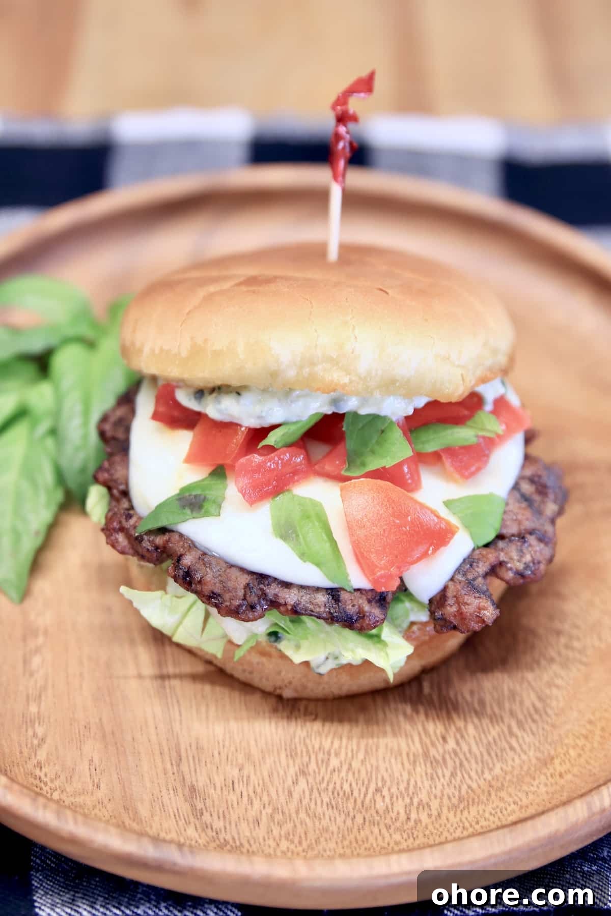 Grilled Caprese Burger Recipe with Fresh Mozzarella & Basil 4 Wood plate with grilled burger, mozzarella, tomato, basil.